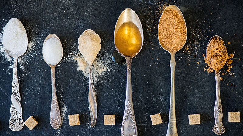 Assorted sweeteners in spoons on dark background Assorted sweeteners in spoons on dark background