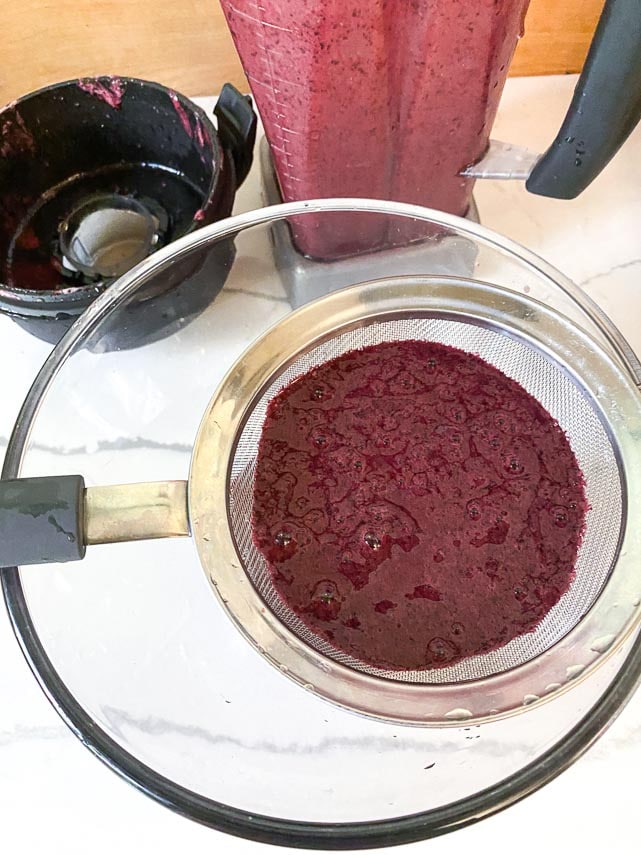 blueberry purée in fine mesh strainer set over glass bowl
