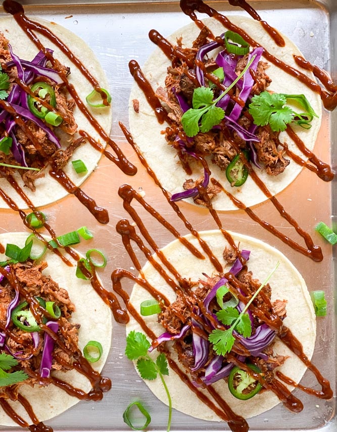 closeup image of low FODMAP pork BBQ tostadas on sheet pan; zig zag of BBQ sauce