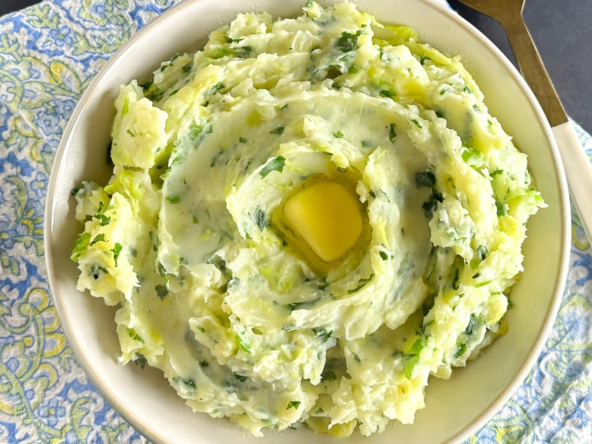 closeup Low FODMAP Colcannon in white bowl with gold spoon