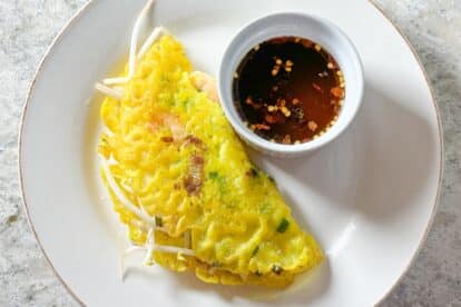 Closeup Low FODMAP Vietnamese Pancake on white plate with Nuoc Cham Dipping Sauce.