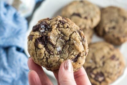 closeup of low FODMAP vegan chocolate chunk cookie sprinkled with salt; held in hand