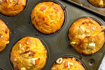 closeup of muffins tins, on the diagonal, holding smoked gouda apple muffins with hazelnuts