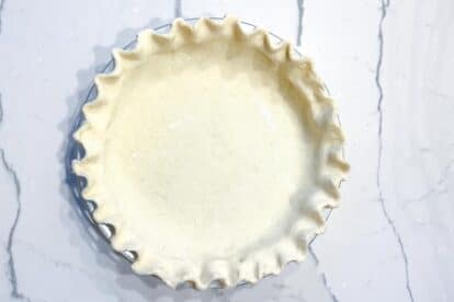 Cream cheese pie crust in pie plate, fluted edge on marble surface-2