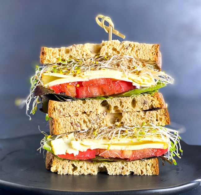 Cutaway of Schar deli bread sandwich with vegetables and cheese on black plate