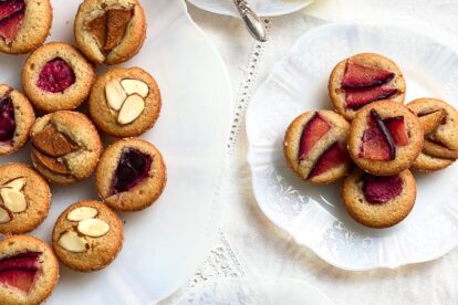 Financiers with various toppings on decorative white plates; tea and teacup at top