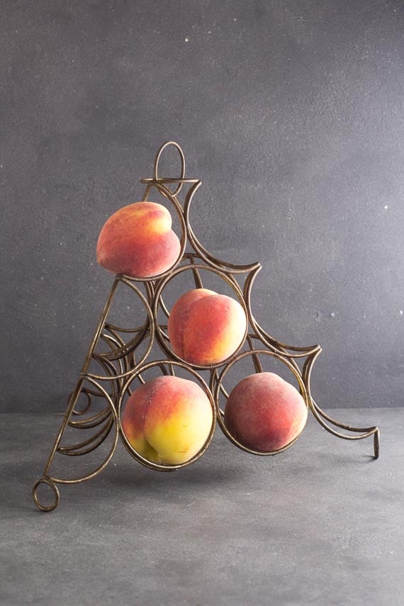 fruit ripening rack on dark background, holding 4 peaches