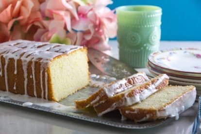 Glazed Low FODMAP Lemon Loaf on tin tray with plates in background