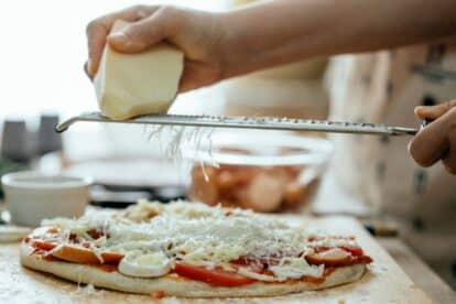 Hand grating cheese over pizza