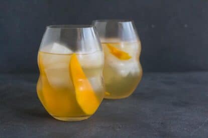 horizontal image of low FODMAP Iced White Tea with Mango in decorative clear glasses on dark background