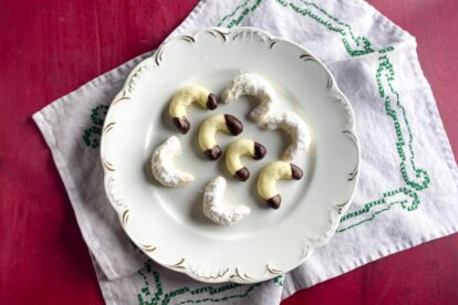 horizontal image of Low FODMAP Vanilla Crescent Cookies on decorative plate; red background