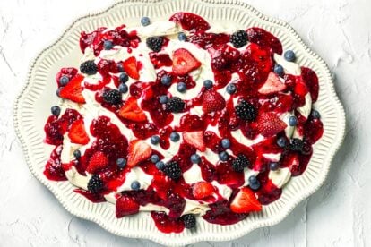 horizontal image of low FODMAP Mixed Berry Slab Pavlova on decorative oval plate; white background