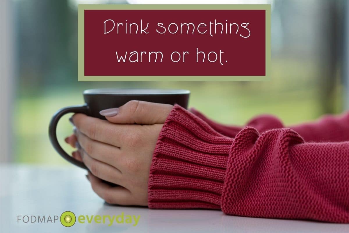 Side view of a woman holding a cup of hot tea in two hands. 