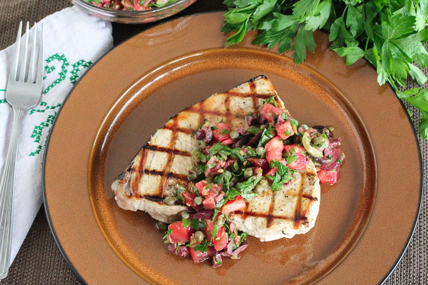 Grilled Swordfish with Tomato Olive Salsa on a brown plate
