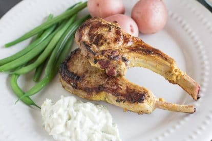lamb chops closeup on white plate with green beans and steamed potatoes
