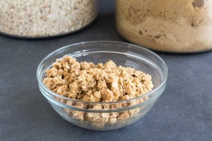 looking down into a bowl of vegan low FODMAP crisp topping in a glass bowl on a dark surface