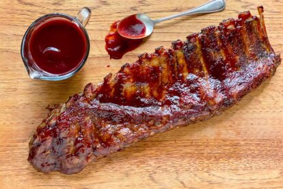 Low FODMAP Blackberry Maple BBQ Rib rack on wooden board with extra sauce