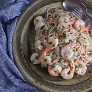 Low FODMAP Buffalo Shrimp Pasta on rustic ceramic plate