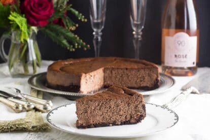 low FODMAP chocolate cheesecake. Whole cake with slcies out in rear; single wedge on white plate up front