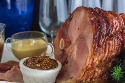 Low FODMAP Cranberry Hot Pepper Glazed Ham on oval white platter with pan juices and assorted mustard-3