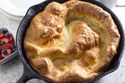 Low FODMAP Dutch Baby Pancake in skillet with berries on the side