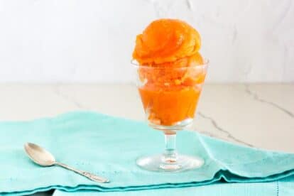 low FODMAP Papaya Lime Sorbet in clear goblet; aqua napkin, white backdrop