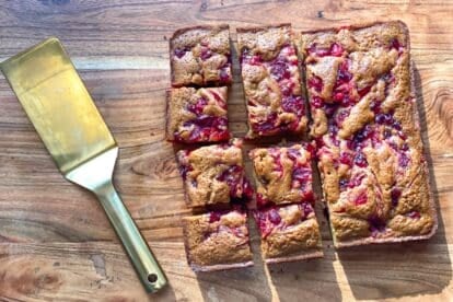 Low FODMAP Sticky Cranberry Gingerbread unmolded on wooden board, pieces cut into squares