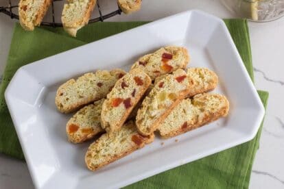 Low FODMAP Tropical Biscotti on white platter with green napkin; cooling on cooling rack in background