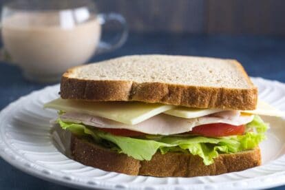 Low FODMAP Turkey & Swiss Sandwich on a white plate; Russian Dressing in background