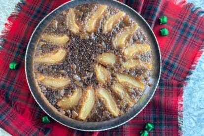 Lower FODMAP Gingerbread Pear Upside Down Cake on silver platter and red plaid napkin beneath.