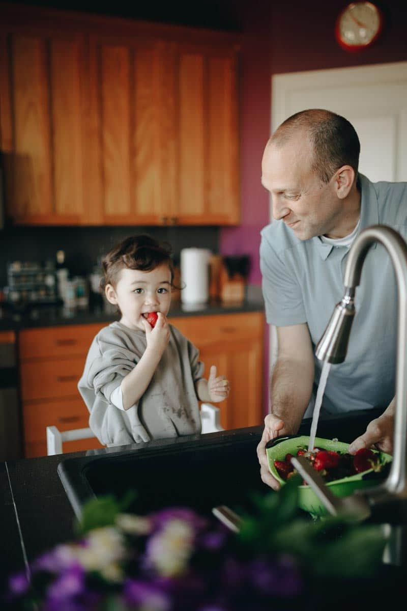 man and child eating strawberries