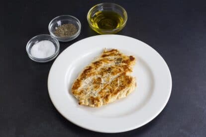 No FODMAP Chicken Paillard on white plate, against dark background