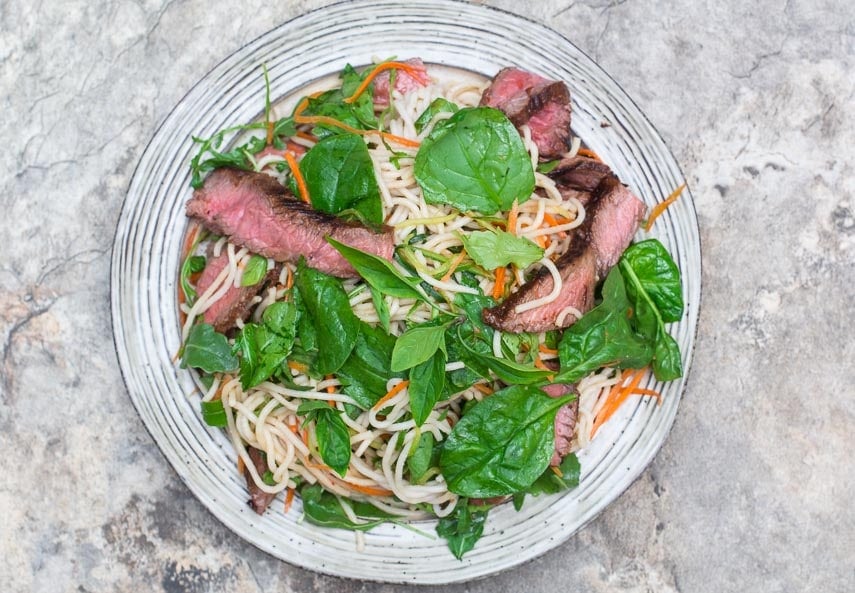 overhead image of Low FODMAP Thai Basil Steak Salad on rustic round white plate overhead image of Low FODMAP Thai Basil Steak Salad on rustic round white plate