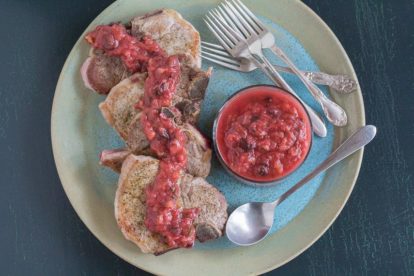 overhead image of spiced rhubarb chutney with juicy pork chops on blue platter