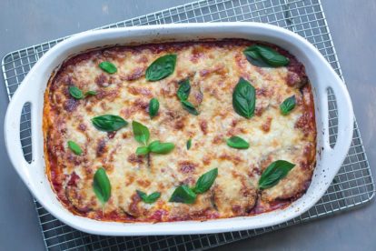 overhead view of low FODMAP eggplant parmigiana in white casserole on cooling rack
