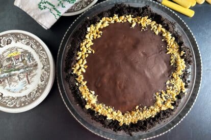low FODMAP Chocolate Peanut Butter Pie, dark background; antique plates, silverware and embroidered napkin
