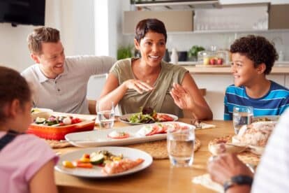 Multi-Generation Mixed Race Family Eating Meal Around Table At Home Together
