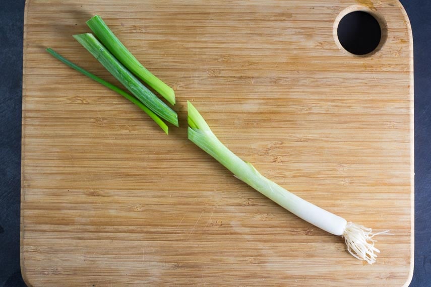 scallion on cutting board, scallion greens separated from white portion
