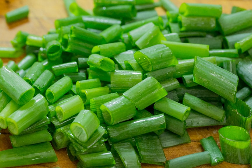 scallion greens roughly chopped on wooden cutting board, closeup
