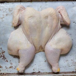 spatchcock chicken, raw with wings tucked