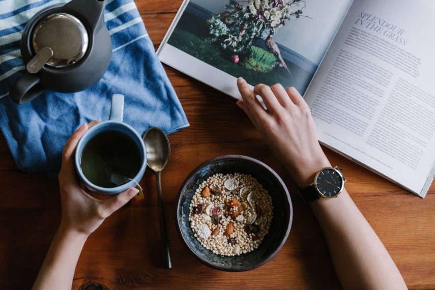 A person sitting reading with a bowl of granola and coffee -The Low FODMAP Diet Elimination Phase: Short & Sweet for Your Health!