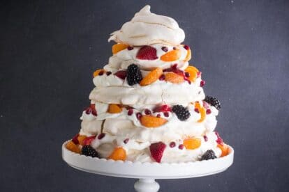 Towering Low FODMAP Fruit Pavlova, horizontal, against dark background