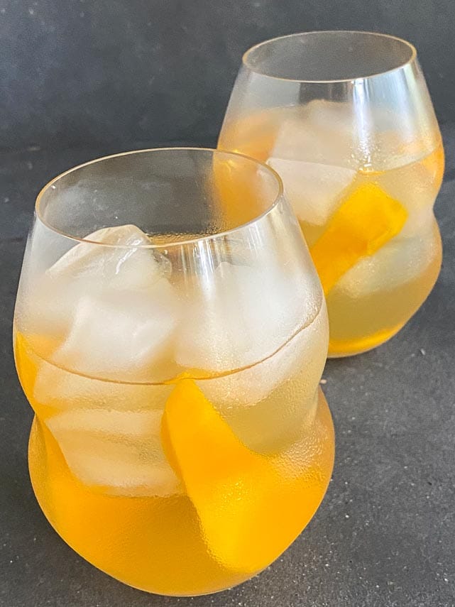 two glasses of low FODMAP Iced White Tea with Mango in decorative clear glasses on dark background