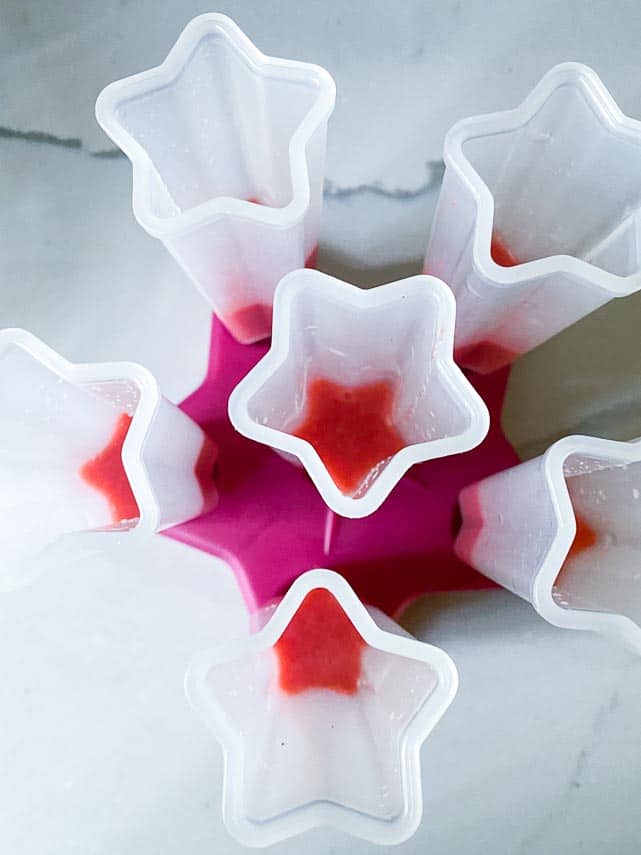 vegan red, white and blue low FODMAP pops being made, showing strawberry layer