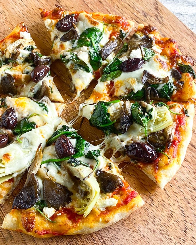 vegetable topped sourdough pizza, closeup, on board
