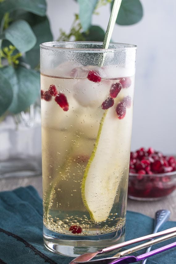 vertical image of low FODMAP ginger pomegranate pear sparkler with stirrer