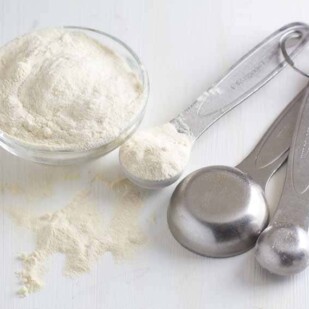 Powdered xantham gum in bowl and measuring spoon.