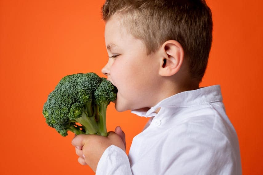young boy enjoying raw broccoli